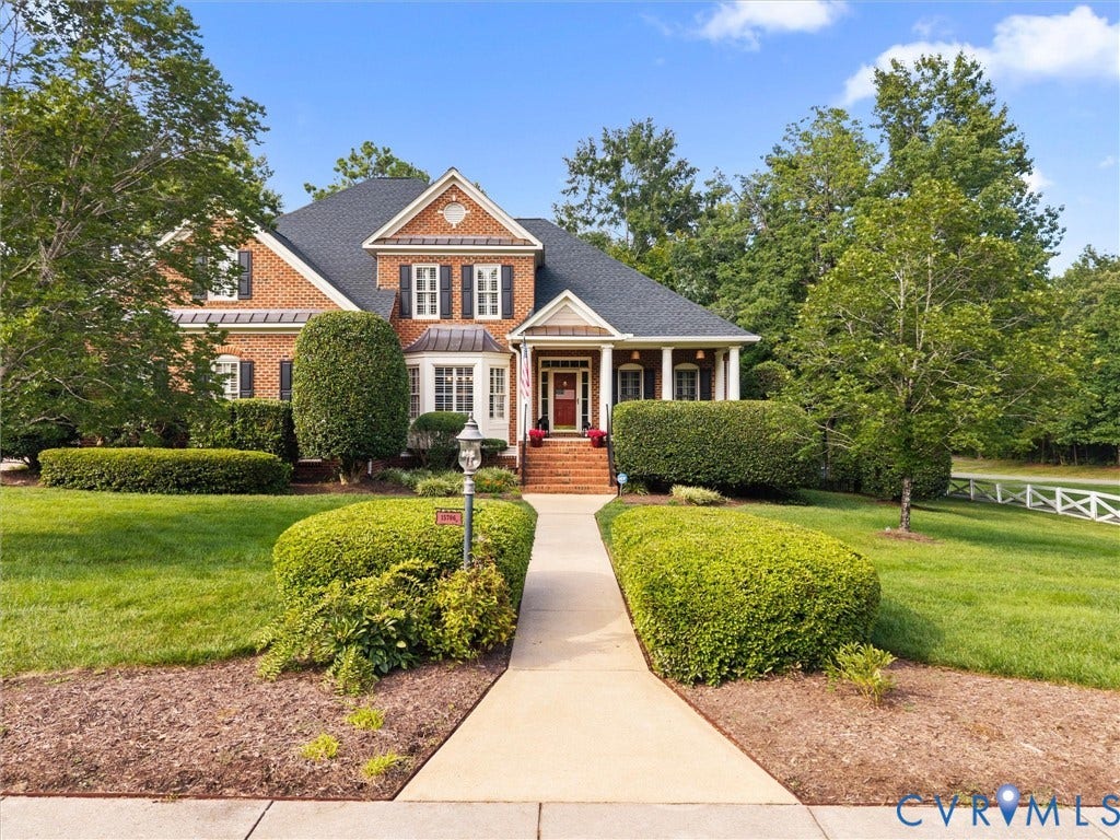 15706 Fox Marsh Drive, Moseley, VA 23120 Brick exterior with white trim, formal landscaping, columned porch, and a white picket fence