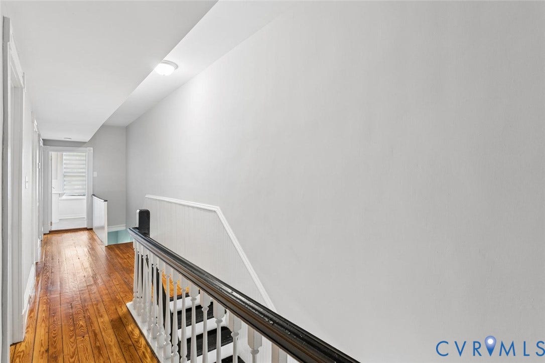 313 W 27th Street, Richmond, VA 23225 Bright upper-level hallway featuring hardwood flooring, angled ceiling with recessed lighting, white painted walls, and a decorative stair railing with black metal accents and white balusters