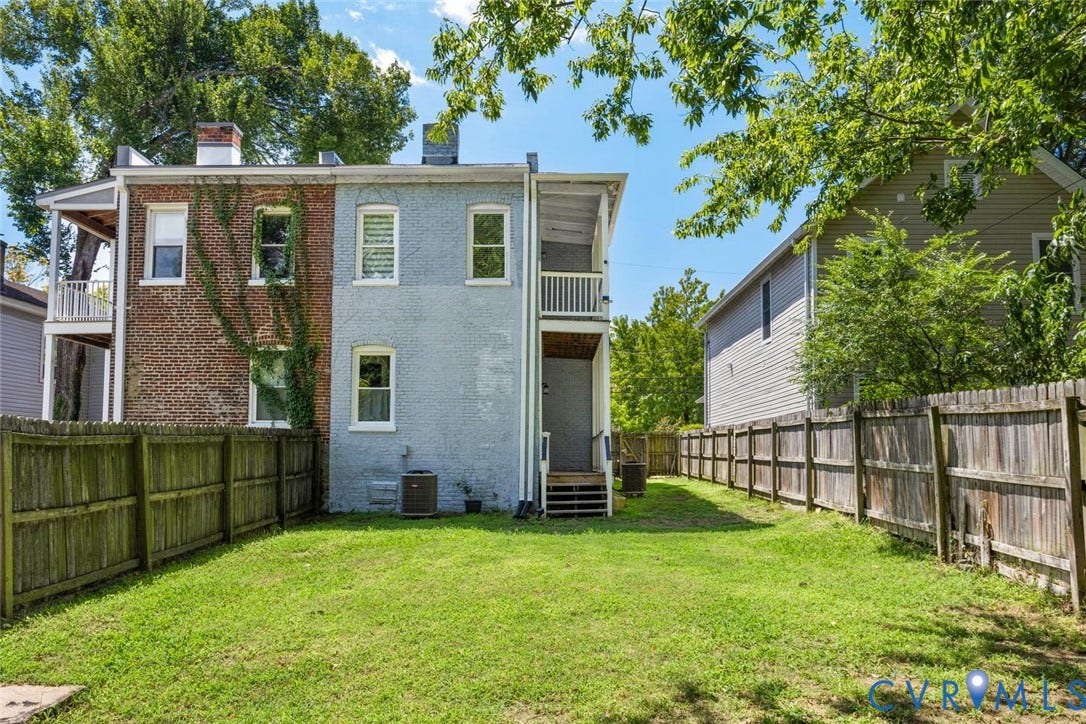313 W 27th Street, Richmond, VA 23225 Fenced backyard featuring a manicured lawn, brick and stucco exterior, and a two-story back porch