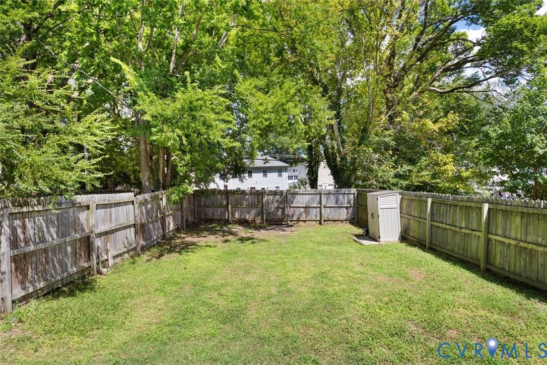 313 W 27th Street, Richmond, VA 23225 Fenced backyard featuring a storage shed and mature trees