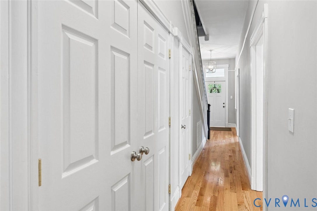 313 W 27th Street, Richmond, VA 23225 Hardwood flooring throughout the hallway, white paneled doors, and a decorative ceiling light fixture