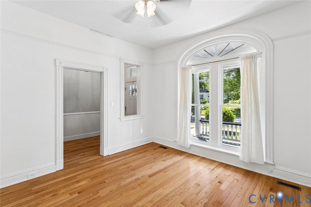 313 W 27th Street, Richmond, VA 23225 Hardwood flooring, arched window with decorative transom, built-in ceiling fan, white trim, and a cased opening