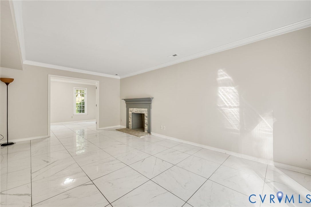 4820 Cedar Cliff Road, Chester, VA 23831 White large-format tile flooring, gray mantel fireplace with stone surround, crown molding, wide doorway, and a double window with muntins in the background