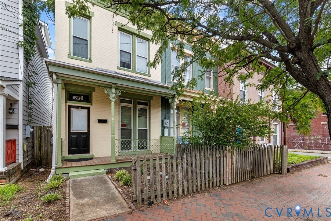 1202 1/2 W Clay Street, Richmond, VA 23220 Two-story facade with light-colored siding, green trim accents, and a covered front porch featuring decorative columns