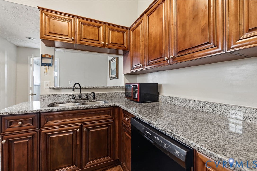 1202 1/2 W Clay Street, Richmond, VA 23220 Wood cabinetry with decorative paneling, granite countertops, stainless steel double basin sink, and a black gooseneck faucet