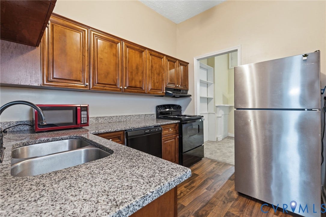 1202 1/2 W Clay Street, Richmond, VA 23220 Wood-finish flooring, granite-style countertops, stainless steel refrigerator, dark wood cabinetry, and a black electric range