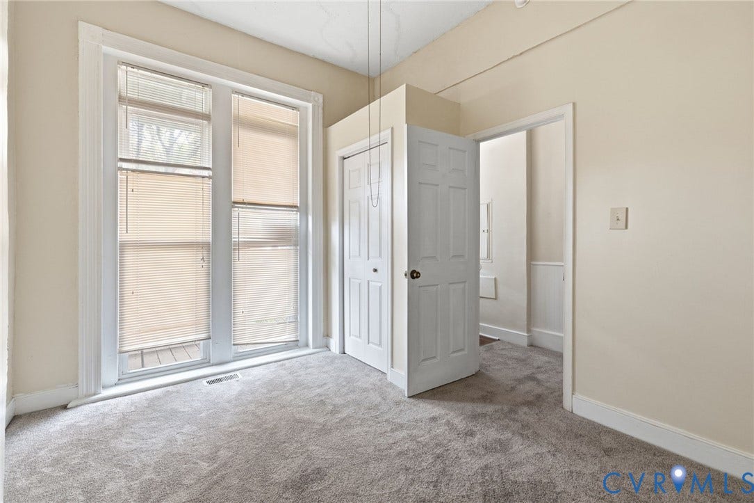 1202 1/2 W Clay Street, Richmond, VA 23220 Carpeted room featuring large windows with blinds, a bi-fold closet, and a paneled door