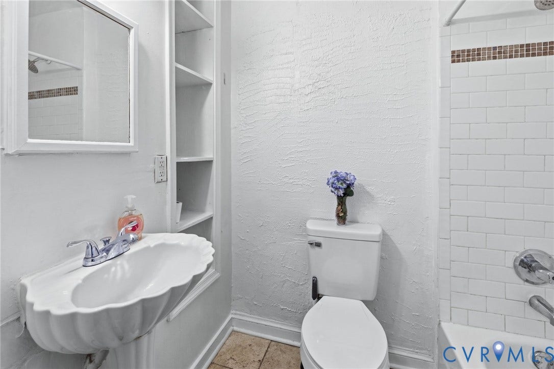 1202 1/2 W Clay Street, Richmond, VA 23220 Pedestal sink with chrome faucet, built-in shelving, white subway tile shower surround with mosaic accent, and white toilet