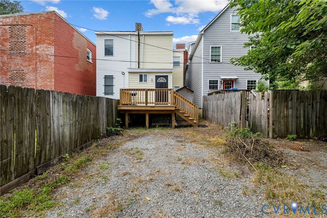1202 1/2 W Clay Street, Richmond, VA 23220 Rear exterior featuring a wood deck with stairs, a gravel-surfaced yard, and a wood privacy fence