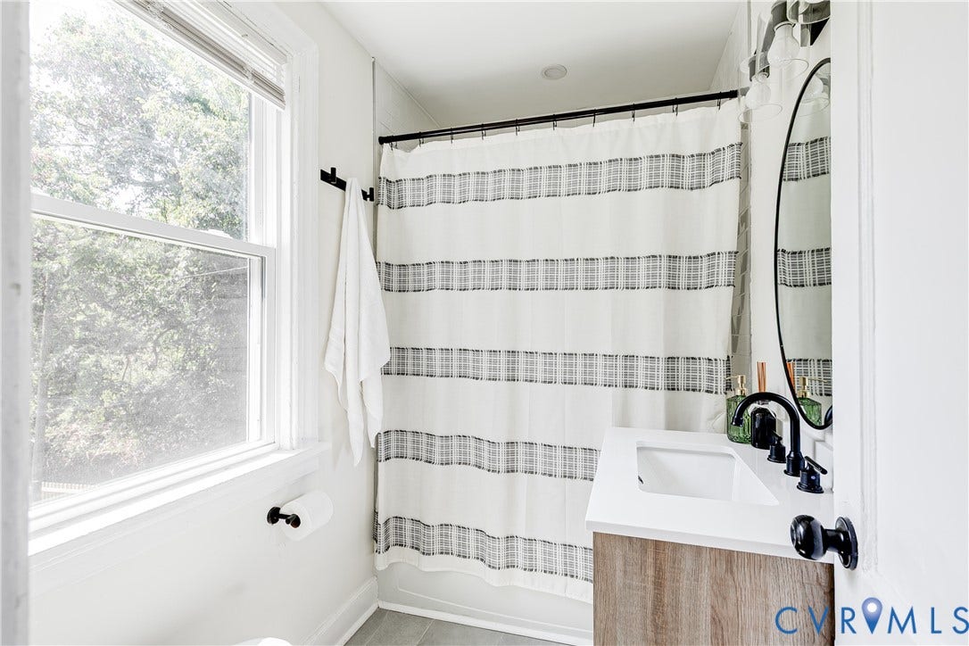 3215 Detroit Avenue, Richmond, VA 23222 Single-pane window, wood-finish vanity with integrated sink, black faucet, and black shower rod