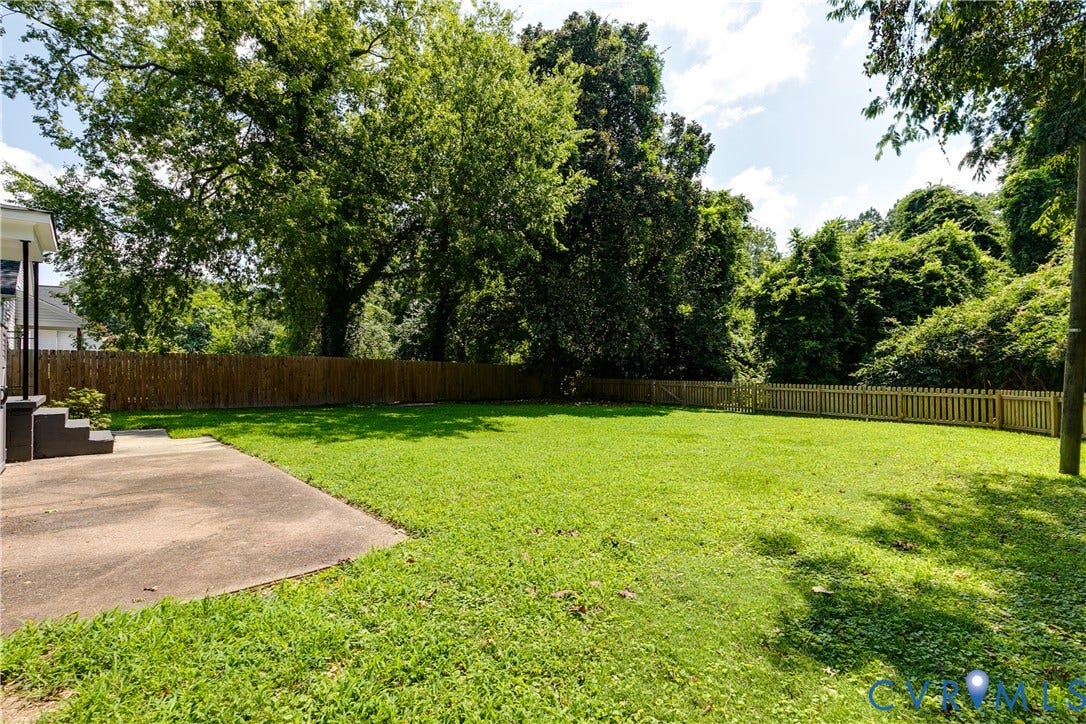 3215 Detroit Avenue, Richmond, VA 23222 Expansive green lawn, wood privacy fencing, concrete patio, mature trees, and exterior stairs