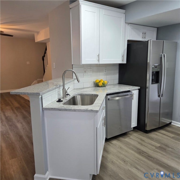 3241 Ransom Hills Road, Chesterfield, VA 23237 Modern kitchen featuring white shaker cabinetry, stainless steel appliances, a subway tile backsplash, light-colored countertops, and wood-finish flooring