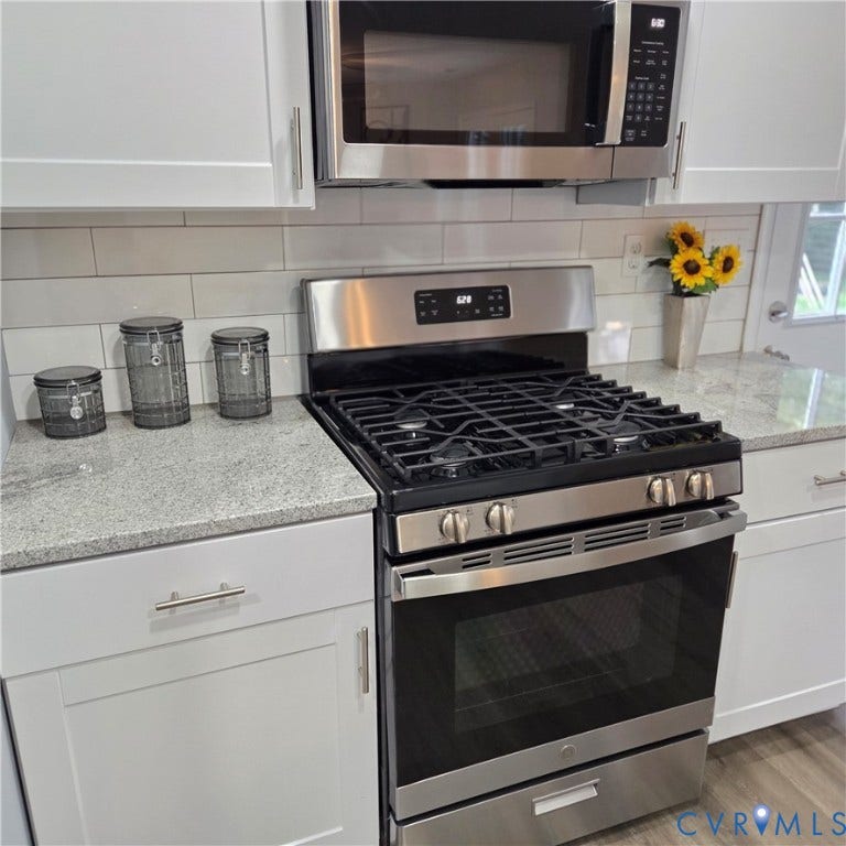 3241 Ransom Hills Road, Chesterfield, VA 23237 Stainless steel gas range with coordinating microwave, white subway tile backsplash, light-toned countertops, and white shaker-style cabinetry