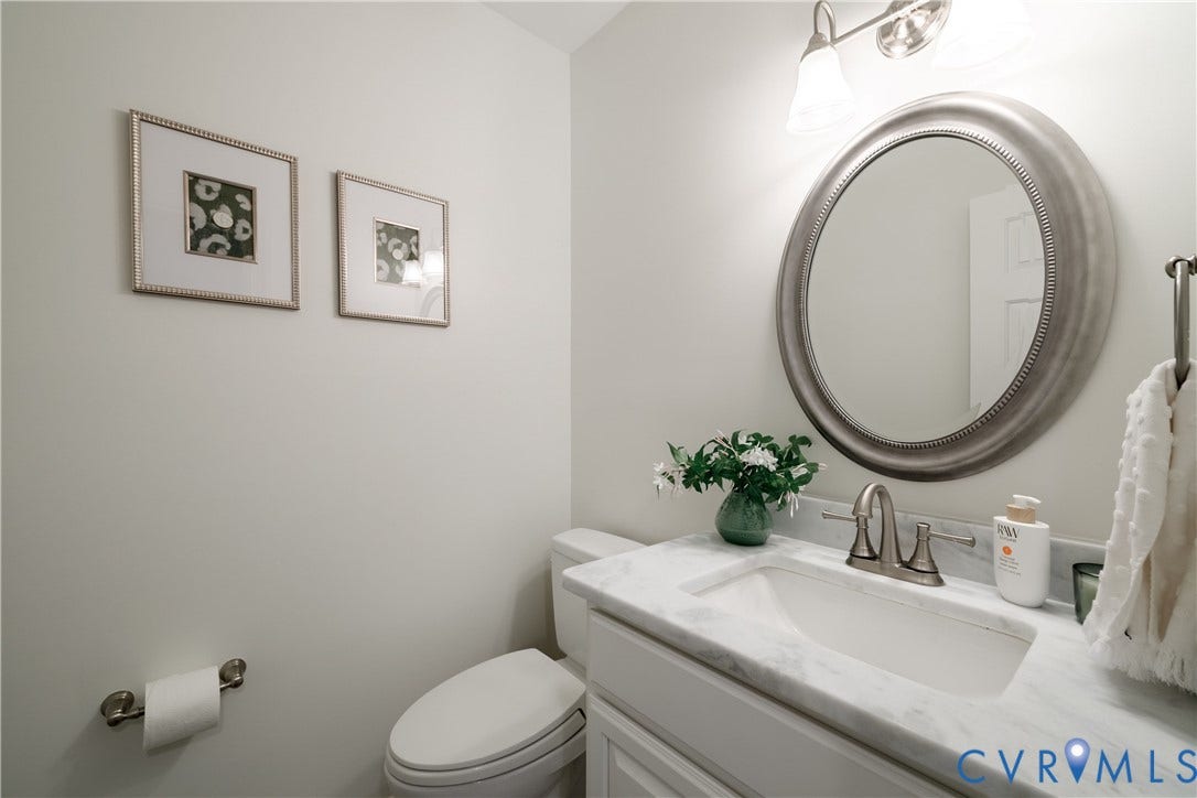 300 N Ridge Road, #97, Henrico, VA 23229 First floor powder room with marble-topped vanity, undermount sink, brushed nickel faucet, and a round framed mirror