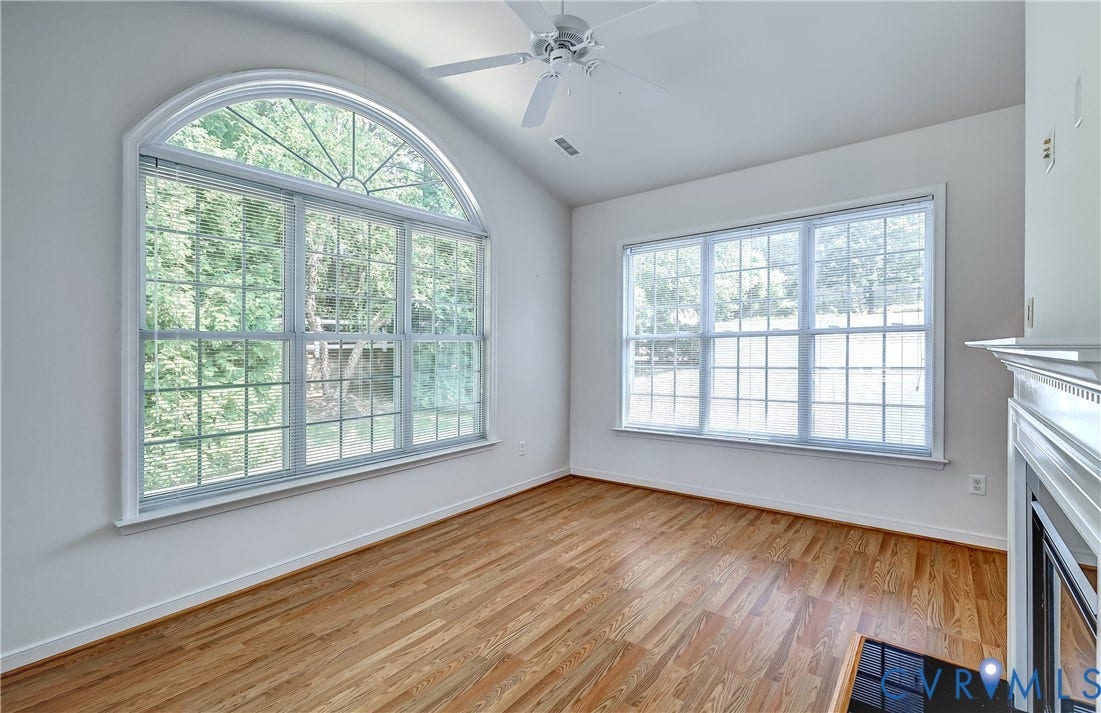 5046 Lewisetta Drive, Carriage Homes II Crossridge, Glen Allen, VA 23060 Hardwood flooring, vaulted ceiling, arched window, ceiling fan, and a fireplace with a white mantel and black surround