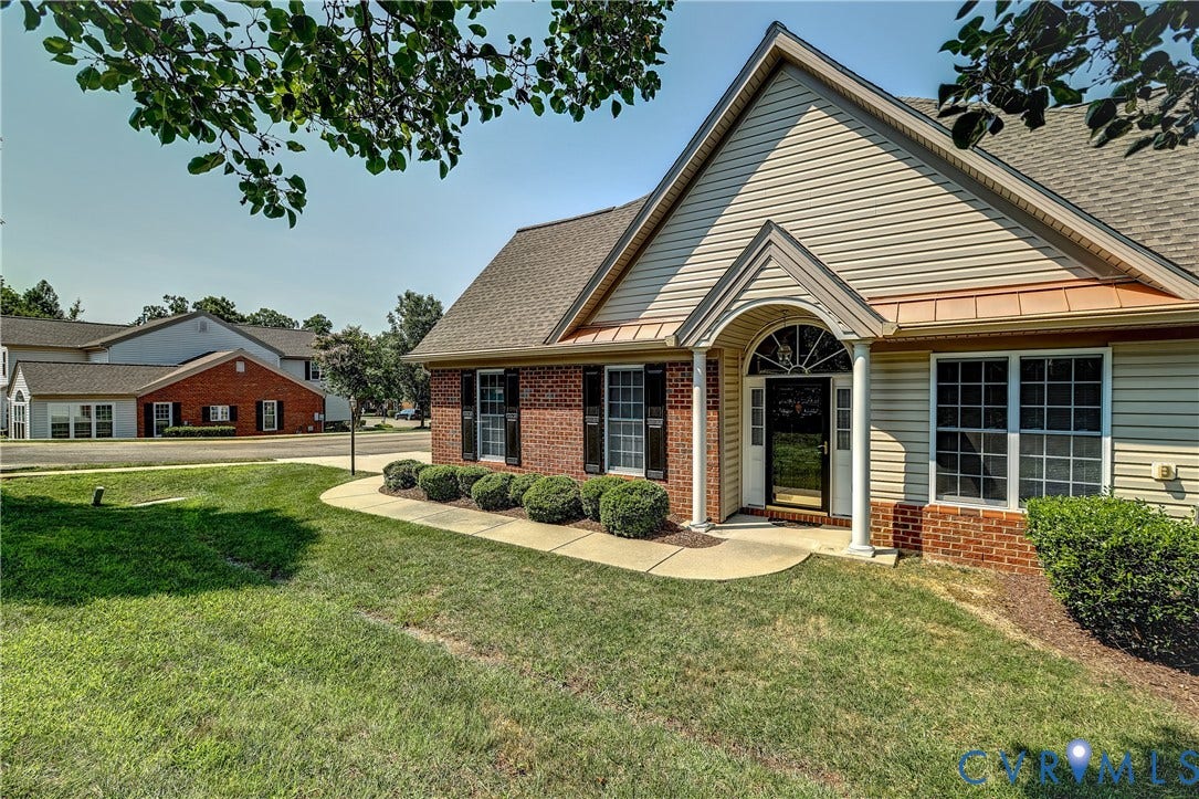 5046 Lewisetta Drive, Carriage Homes II Crossridge, Glen Allen, VA 23060 Brick and siding exterior featuring a covered entry, arched transom window, shuttered windows, and a manicured lawn
