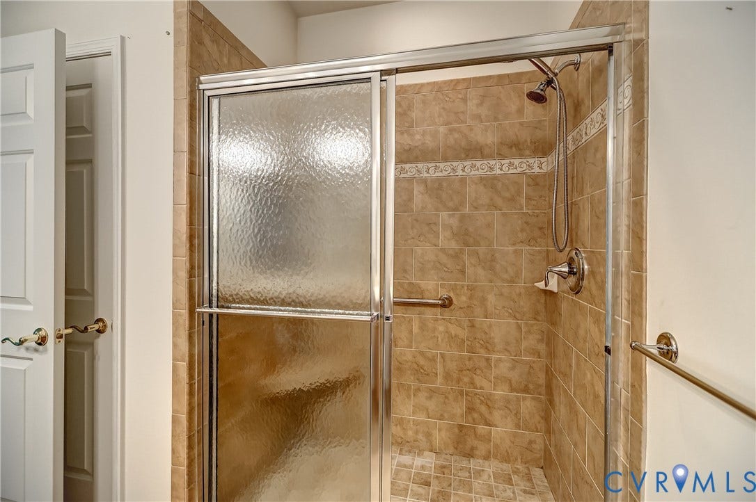 5046 Lewisetta Drive, Carriage Homes II Crossridge, Glen Allen, VA 23060 Enclosed shower featuring textured glass doors, full-height tile surround, decorative tile accent band, and integrated grab bars