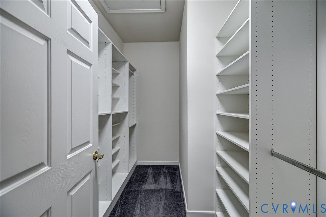 5046 Lewisetta Drive, Carriage Homes II Crossridge, Glen Allen, VA 23060 Walk-in closet with extensive built-in shelving, white paneled door, and dark carpet flooring