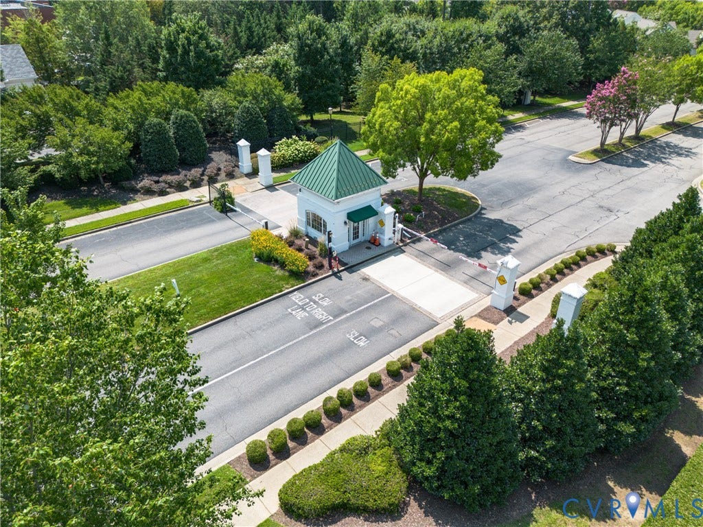 5046 Lewisetta Drive, Carriage Homes II Crossridge, Glen Allen, VA 23060 Gated community entrance featuring a guardhouse with a green roof, manicured landscaping, and mature trees