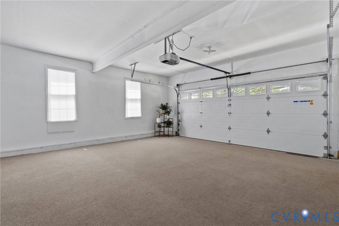 3242 Sherwood Ridge Drive, Powhatan, VA 23139 Spacious garage featuring a large automatic overhead door with upper window panels, two side windows, and light-toned carpeting