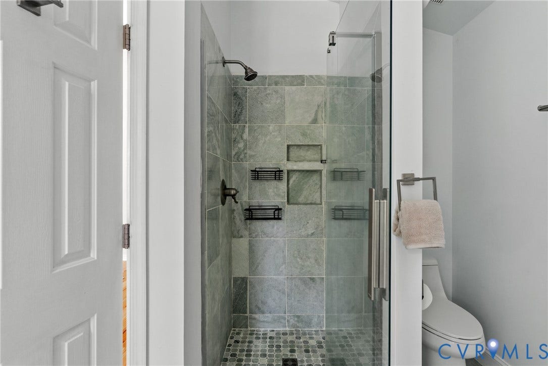 3242 Sherwood Ridge Drive, Powhatan, VA 23139 Tiled shower enclosure featuring glass paneling, a rain showerhead, and integrated shelving
