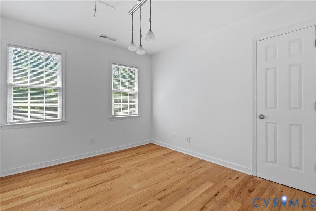 3242 Sherwood Ridge Drive, Powhatan, VA 23139 Wood-finish flooring, white walls, two double-hung windows, and a three-light pendant fixture