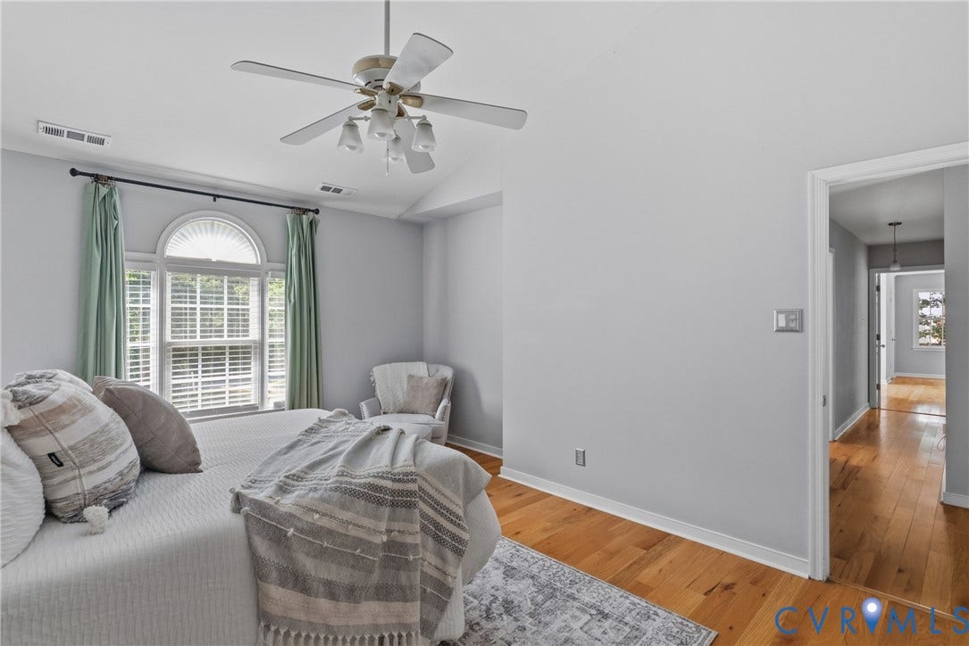 3242 Sherwood Ridge Drive, Powhatan, VA 23139 Arched window with louvered blinds, vaulted ceiling, ceiling fan with light kit, wood-finish flooring, and recessed doorway