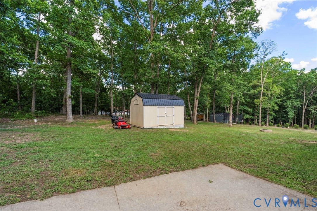 3242 Sherwood Ridge Drive, Powhatan, VA 23139 Spacious backyard featuring a concrete patio, mature trees, and a detached storage shed