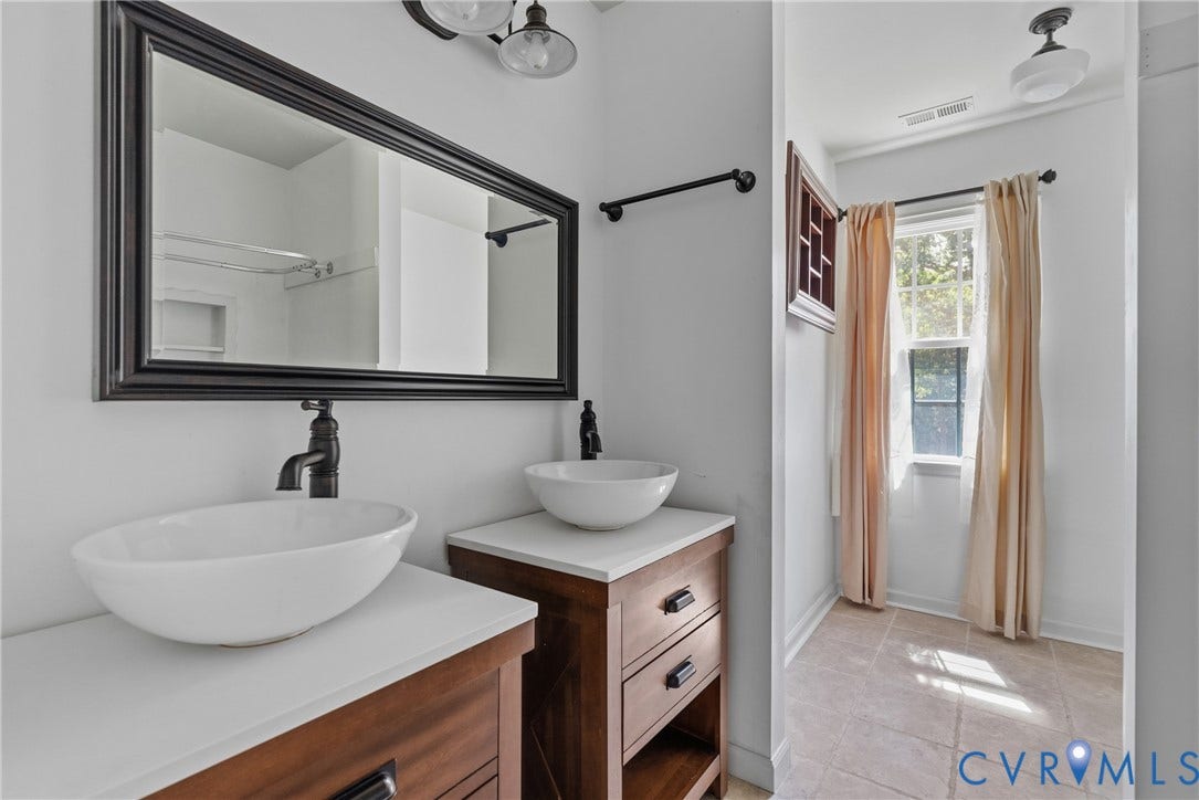 3242 Sherwood Ridge Drive, Powhatan, VA 23139 Dual vessel sinks with dark bronze fixtures, wood-finish vanities with drawer storage, and a framed wall mirror
