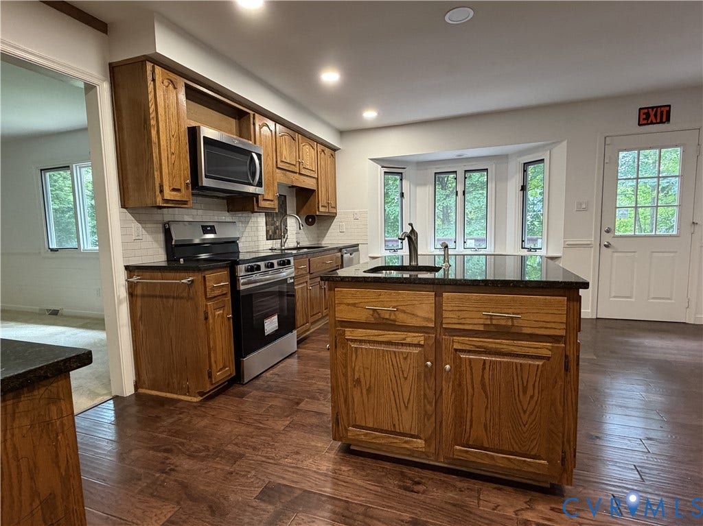 4603 Edenton Place, Greenbriar, Chester, VA 23831 Kitchen featuring wood-finish flooring, wood cabinetry, dark countertops, and stainless steel appliances including a range and microwave