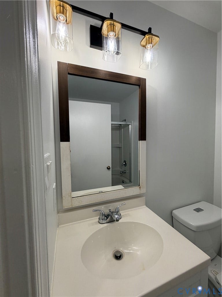 4603 Edenton Place, Greenbriar, Chester, VA 23831 Vanity with integrated sink and chrome faucet, framed mirror, and modern three-light fixture with gold-tone accents