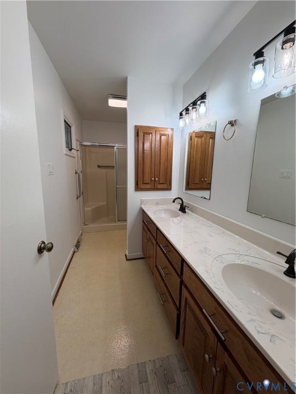 4603 Edenton Place, Greenbriar, Chester, VA 23831 Dual vanity with integrated sinks and white countertops, wood-finish cabinetry with silver-tone hardware, wall-mounted light fixtures, and a shower with a sliding glass door