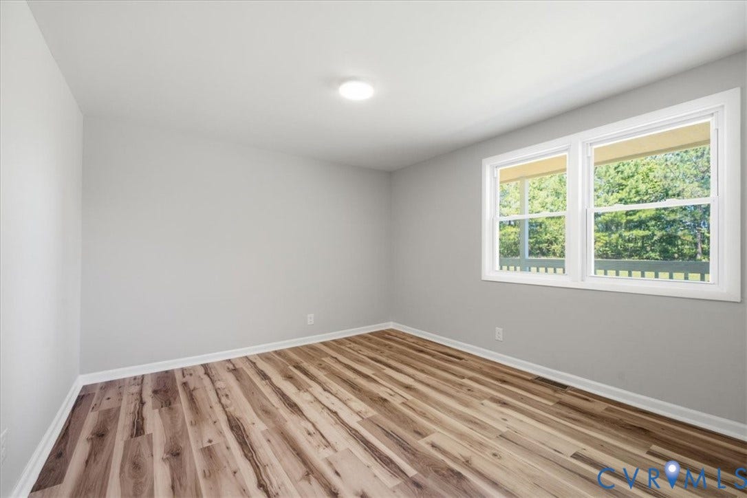 16111 Walkers Mill Road, Stony Creek, VA 23832 Bright, light-filled bedroom featuring newly installed wood-finish flooring, neutral painted walls, and dual casement windows with natural light exposure
