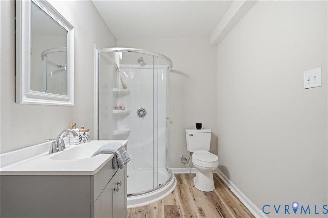 16111 Walkers Mill Road, Stony Creek, VA 23832 Wood-finish flooring, white walls, and a curved glass shower enclosure define this bathroom