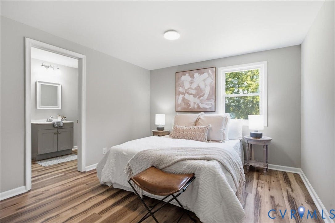 16111 Walkers Mill Road, Stony Creek, VA 23832 Wood-finish flooring, light grey painted walls, ceiling-mounted light fixture, window with white trim, and a full bathroom with a grey vanity