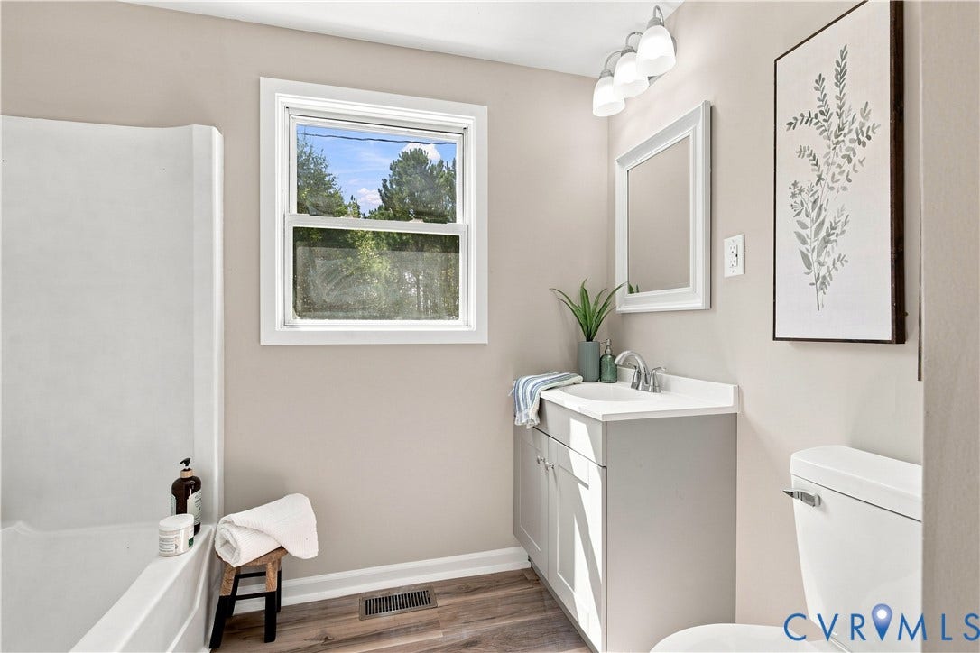 16111 Walkers Mill Road, Stony Creek, VA 23832 Bathroom featuring wood-finish flooring, a white vanity with an integrated sink, a framed mirror, and a full-size bathtub