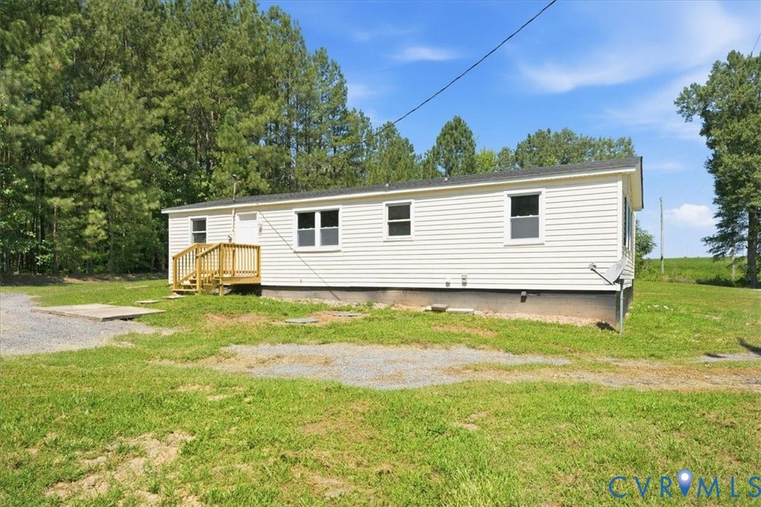 16111 Walkers Mill Road, Stony Creek, VA 23832 White horizontal siding, dark shingle roof, natural wood deck, and a gravel driveway
