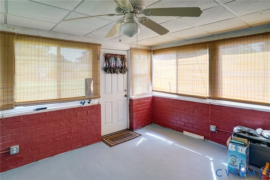 10104 Terry Court, Henrico, VA 23228 Sunroom featuring a ceiling fan, multiple windows with bamboo blinds, a white paneled door, and red brick knee walls