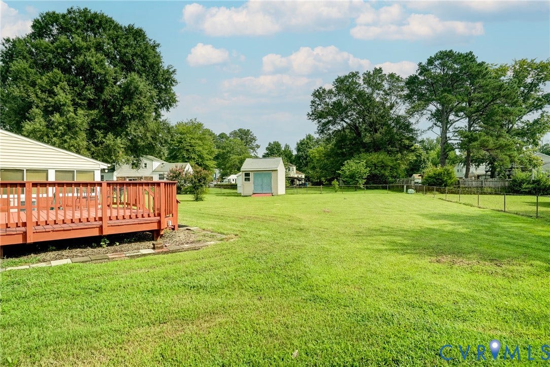 10104 Terry Court, Henrico, VA 23228 Expansive grassy yard featuring a wooden deck, a storage shed, and mature trees