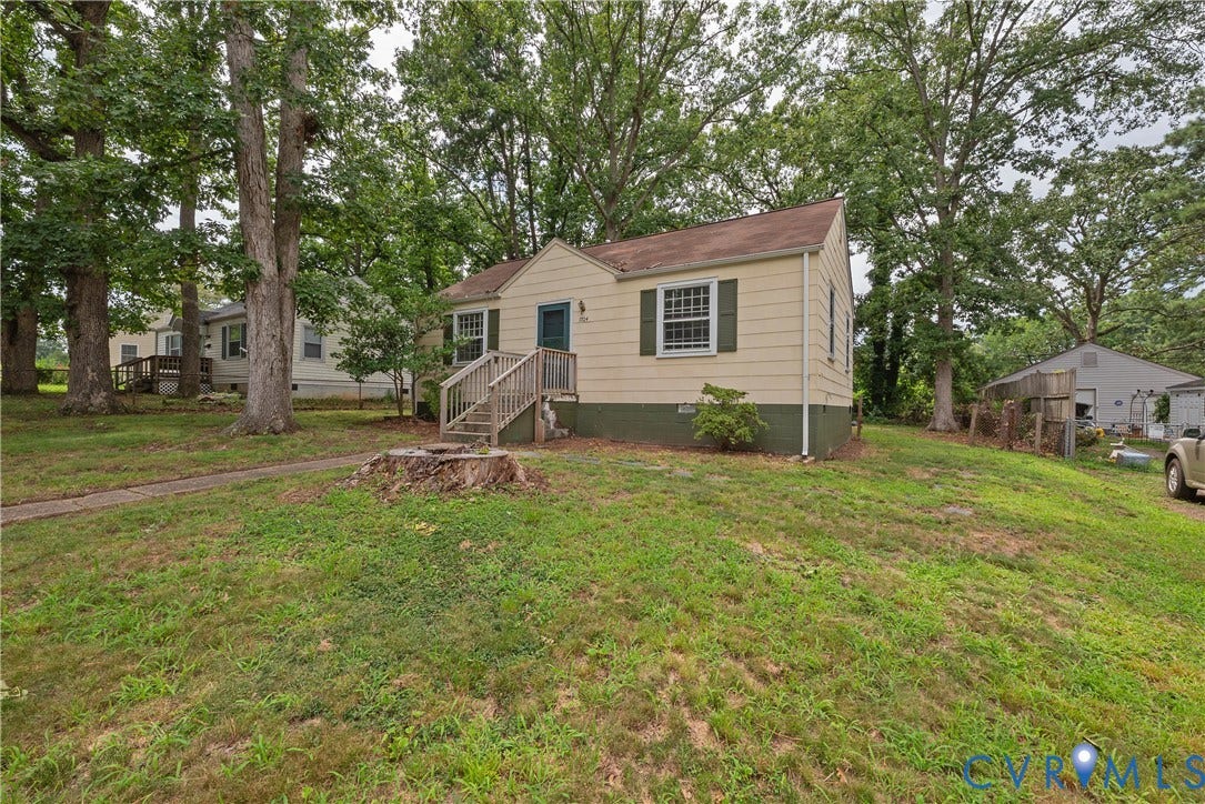 1704 Westhill Road, Richmond, VA 23226 Siding exterior with a pitched roof, front entry stairs, mature trees, and a sloped lawn