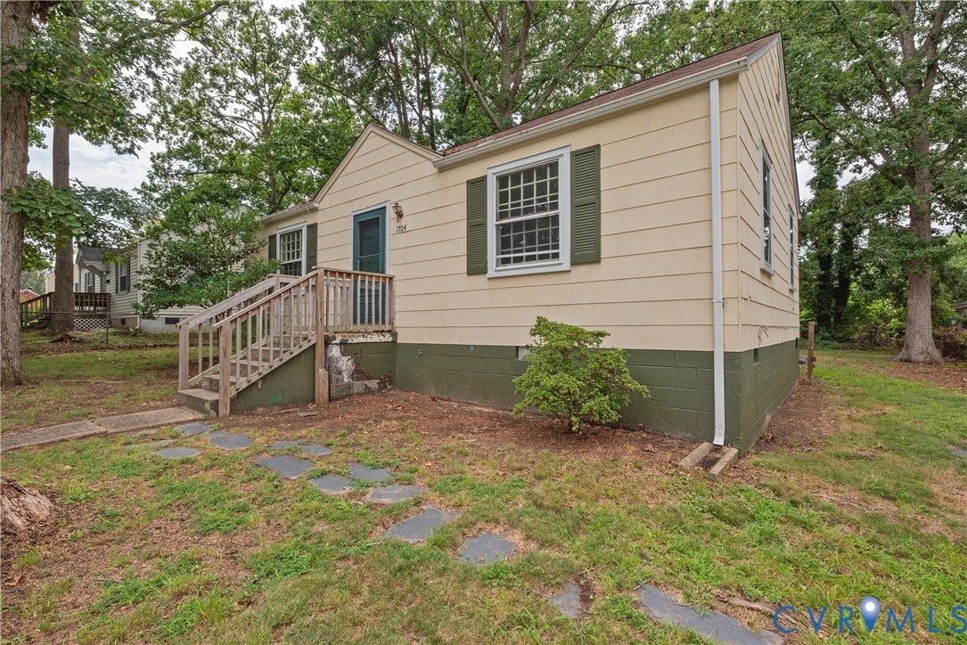 1704 Westhill Road, Richmond, VA 23226 Cottage-style residence featuring horizontal siding, dark green window shutters, and a front entry with a wood-tone staircase and railing