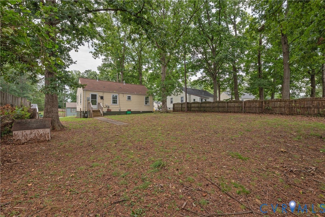 1704 Westhill Road, Richmond, VA 23226 Expansive backyard featuring mature trees, a privacy fence, and a pathway leading to the residence