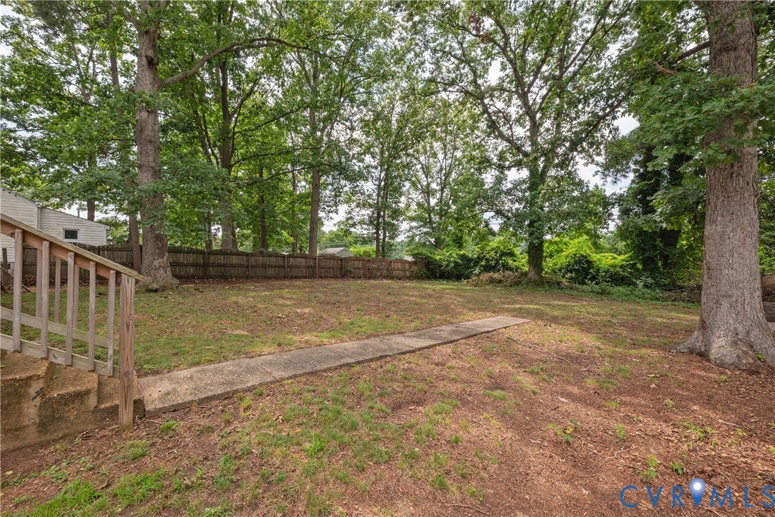 1704 Westhill Road, Richmond, VA 23226 Expansive backyard with a level lawn, mature trees, wood fence, and a concrete pathway