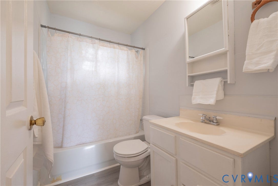 1704 Westhill Road, Richmond, VA 23226 Hall Bath with White wood-finish vanity with an integrated sink, chrome faucet, and white framed mirror and tub/shower combination.