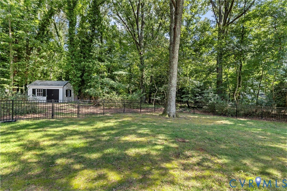 13531 W Salisbury Road, Salisbury, Midlothian, VA 23113 Expansive lawn area with a black metal fence, mature trees, and a detached shed featuring a white exterior and dark shutters