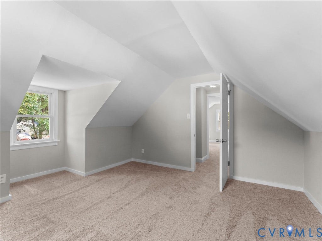 4818 Castlewood Road, Richmond, VA 23234 Bright attic bedroom featuring sloped ceilings, carpeted flooring, and a large window with natural light
