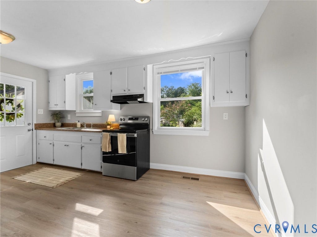 4818 Castlewood Road, Richmond, VA 23234 Bright kitchen featuring white cabinetry, stainless steel appliances, wood-finish flooring, and abundant natural light from multiple windows