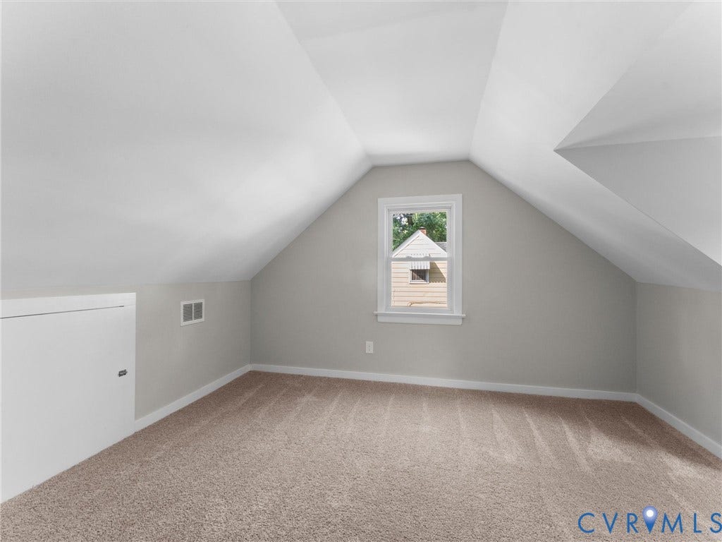 4818 Castlewood Road, Richmond, VA 23234 Bright, airy attic room with vaulted ceilings, abundant natural light from a large window, and neutral wall finishes
