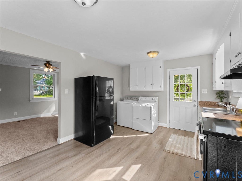 4818 Castlewood Road, Richmond, VA 23234 Open-concept kitchen and laundry area featuring white cabinetry, stainless steel appliances, wood-finish flooring, and abundant natural light from multiple windows