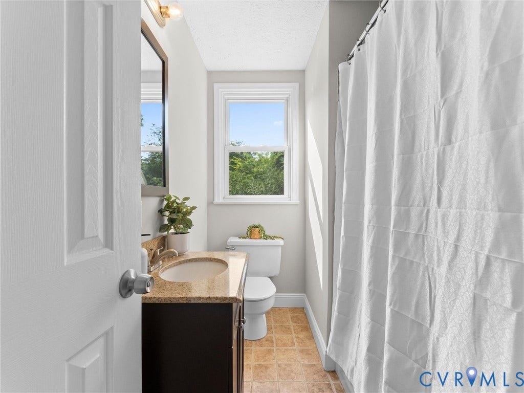 4818 Castlewood Road, Richmond, VA 23234 Single-pane window, vanity with a light-toned countertop, sink with a faucet, toilet, and tiled flooring